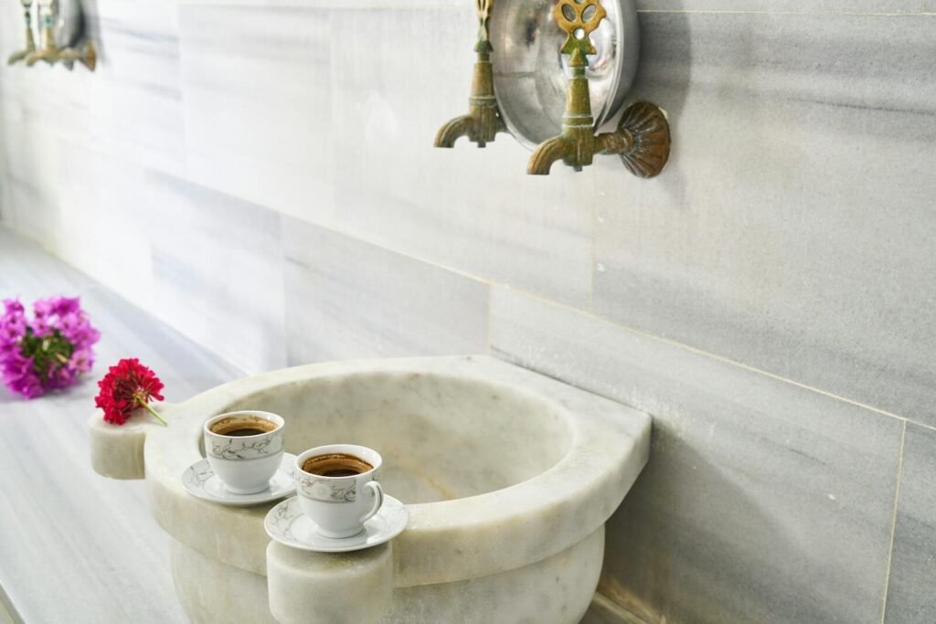 Turkish coffee cups elegantly placed on a marble sink with ornate faucets, evoking a traditional aesthetic.