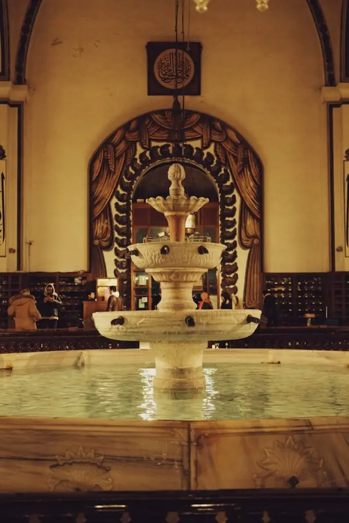 Elegant indoor fountain in a historic hall with Middle Eastern decor.