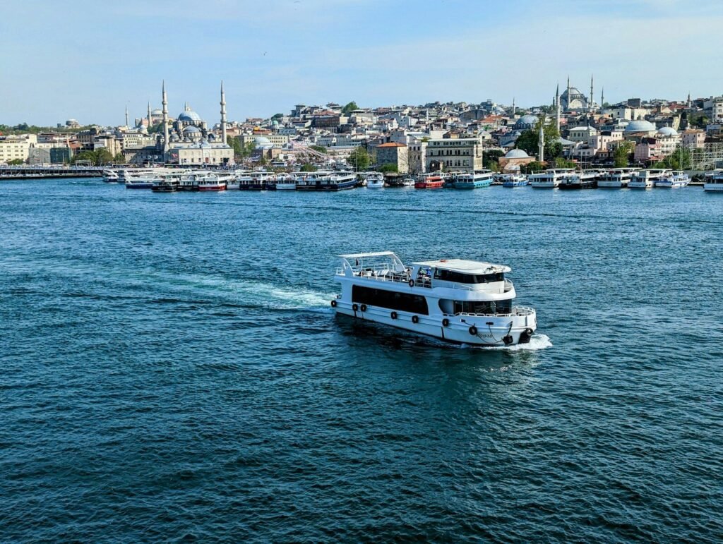 a white boat traveling down a river next to a city